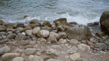 Dalgalar Cala Deia 'nın kayalık sahillerine çarpıyor. Mallorca' nın çeşitli büyüklükteki kaya ve çakıl taşları sahile saçılmış.