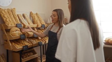 Fırında çeşitli somunlar sergilenen bir müşteriye ekmek seçeneklerini açıklayan kadın fırıncı..