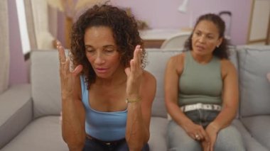 Oturma odasındaki kanepede oturup duygularını ifade eden ve aile meselelerini tartışan kadınlar.