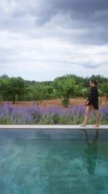 Mallorca İspanya 'da bikini ve lavanta tarlası olan siyah gömlek ve bulutlu gökyüzünün altında arka planda ağaçlarla bilardo oynayan kadın.