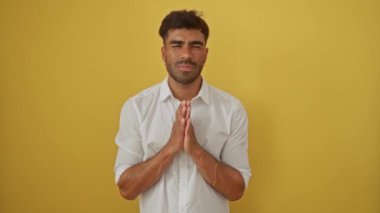 Sarı arka planda yalnız dua eden genç bir İspanyol.