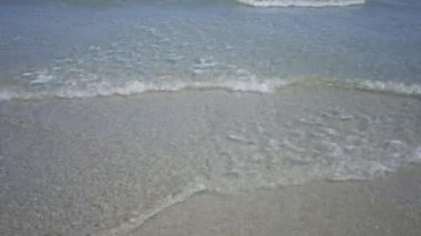 Sakin deniz manzarası, berrak suyla çakıllı bir kumsalda yavaşça süzülüyor güneşli bir günde boş bir sahil şeridinin dingin güzelliğini yakalıyor.