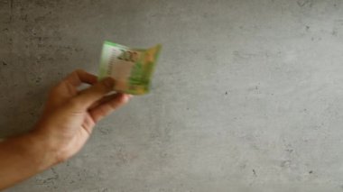 Bir Rus 'u tutarken 200 rublelik banknot beton bir zemine dayanır.