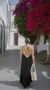 Lanzarote, Hara 'da büyüleyici bir caddede yürüyen canlı bir bougainvillaea ile, kamış sepeti taşıyan, güneşli bir kanarya adasının güzelliğini yakalayan bir kadın. 