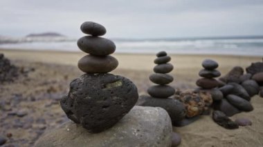 Aile plajlarında gün ışığında kaya yığınları, lanzarote, kanarya adaları, pürüzsüz çakıl taşları ve sakin bir okyanus arka planı olan açık hava manzarası.