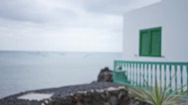 Kanarya adalarında bulutlu gökyüzünün altında bulanık sahil evi ve deniz manzarasıyla Lanzarote 'daki açık hava manzarası
