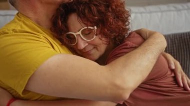 Erkek ve kadın kapalı bir salonda sevgi dolu bir şekilde kucaklaşıyorlar, güçlü bir bağ ve şefkat gösteriyorlar.