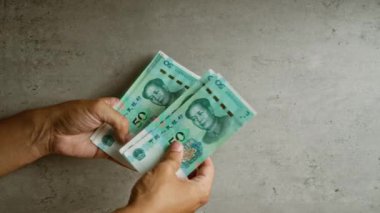 Çin 'deki mali işlemleri temsil eden somut bir arkaplan karşısında Çin Yuan para birimini tutan eller