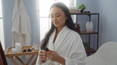 Bir kadın kozmetik ürününü kapalı bir yerde tutarken gülümsüyor, güzellik ürününü kaplıca ortamında sergiliyor, rahatlama ve sağlıklılık öneriyor..