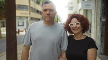 Orta yaşlı çift, canlı bir şehir ortamında sevgi ve birlikteliği yansıtan bir şehir caddesinde kucaklaşıyor..
