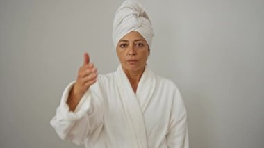 Bornoz ve havlu giymiş orta yaşlı bir kadın ciddi bir ifade takınıyor, gözlerini eliyle kapatıyor, üzüntü ve reddedilme kavramını gizliyor.