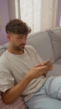 Samimi bir oturma odasında, perdelerden süzülen hafif ışıkla gülümseyen genç bir adam.