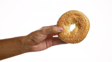 Beyaz arka plan duvarında izole edilmiş susamlı bir simit tutuyorum.
