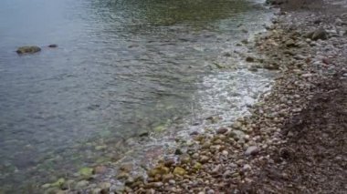 Çakıl taşları ve yosun kaplı taşlarla kayalık kıyılar açık deniz ortamında sakin sularla buluşuyor.