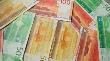 Norveç kron banknotları çeşitli banknotlar, Norveç 'ten gelen renkli para birimi sergileniyor, düz bir yüzeye yayılıyor, kadın Honderd ve 100' lük banknotların karmaşık tasarımlarını vurguluyor.