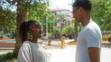 Kadın ve erkek şehir parkında gülümsüyor. Afro-Amerikan aile bağlarını ve aşkı resmediyorlar..