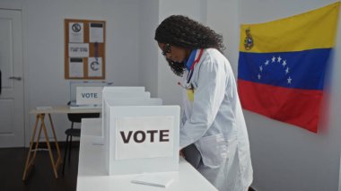 Afrika kökenli Amerikalı bir kadın, Venezuela bayrağı duvarında, kapalı bir üniversite odasında oy veriyor..