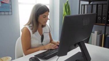 Modern ofis ortamında çalışan bir kadın, profesyonelliği ve dikkati yansıtan, ofis ekipmanları, raf düzenleyicileri ve parlak, motive edici bir çevreyle çevrili,.