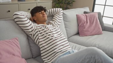 Genç İspanyol adam evdeki rahat bir kanepede dinleniyor, oturma odasında huzurlu bir anın tadını çıkarıyor..