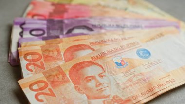 Filipin pesoları, 20 ve 100 'lük banknotlar da dahil olmak üzere renkli banknotlar sergilenen beton bir yüzey üzerinde sergilendi.