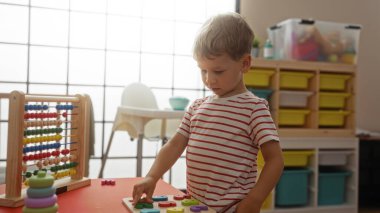 Çocukluğunda anaokulu ortamında evde eğitici oyuncaklarla oynayan küçük çocuk.