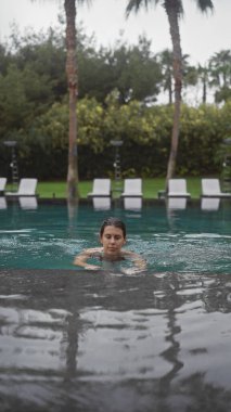Genç bir kadın lüks bir bali tatil köyünün yemyeşil havuzunda yüzerken sükunetin tadını çıkarıyor..