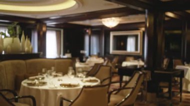 Bokeh ışıklandırması, lüks dekorları olan şık bir restoran ve yastıklı sandalyeler ve modern aydınlatma aletleriyle rafine edilmiş yemek atmosferi yaratan masalar..