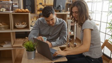 Bir çift, fırın kafede dizüstü bilgisayarda çalışıyor. Etrafı taze ekmek ve hamur işleriyle çevrili.