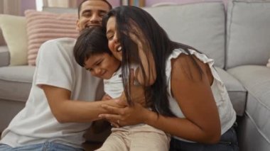 Aile, evde birlikte vakit geçirmenin keyfini çıkarıyor. Evde sevgi dolu bir kadın, erkek ve çocuk, mutluluğu kucaklıyor ve kahkaha atıyor..