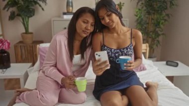 Anne ve kızı rahat bir yatak odasında birlikte oturup kahve içip akıllı bir telefona bakıyorlar. Bir bağ kurma ve aşk anlarını paylaşıyorlar.