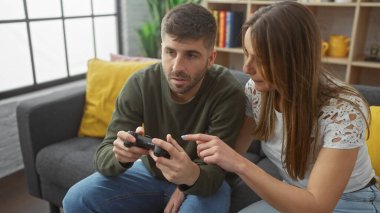 Erkek ve kadın birlikte bir video oyunu oynuyorlar, modern dekorla samimi bir evde kaynaşıyorlar..