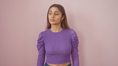 Düşünceli genç bir İspanyol kadın pembe bir arka plana karşı şık, mor bir elbise sergiliyor..