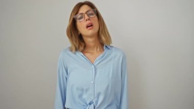 Sarışın, genç, gözlüklü, kolları çapraz beyaz arka plan üzerinde duran, negatif, şüpheci ve sinir bozucu yüz ifadesini onaylamayan bir kadın.