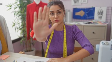 Etrafı kumaşlar ve dikiş malzemeleriyle çevrili bir terzi dükkanında duran İspanyol kadın..