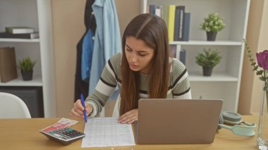 İspanyol kadın evde hesap makinesi ve dizüstü bilgisayarla finans hesapları yapıyor.