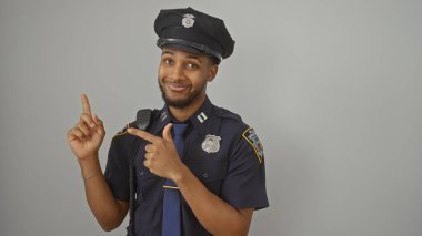 Afro-Amerikan polisi beyaz bir arka plana karşı, dostane bir tavırla işaret ediyor.