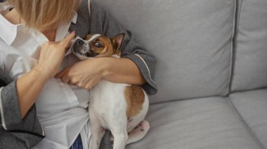 Orta yaşlı bir kadın, rahat bir oturma odasında köpeğinin gözünü temizler ve aile içi ilişkilerine vurgu yapar..