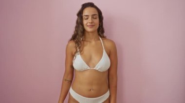 Sekiz numarayı parmaklarıyla gösteren ve bikinili mutlu bir şekilde gülümseyen genç İspanyol kadın izole edilmiş pembe arka planı işaret ediyor.