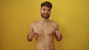 İspanyol asıllı genç bir adamın mutlu bir gülümsemeyle izole edilmiş sarı arka planda üstsüz bir şekilde başarısını kutlamasının kazanan ifadesi.