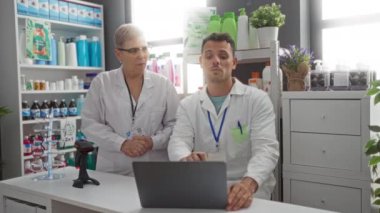 Kadın ve erkek eczacılar tezgahın arkasında, arka planda raflar dolusu ürünlerle parlak bir eczanede tartışıyorlar.