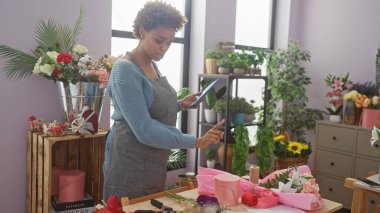 Afro-Amerikalı kadın canlı bir çiçekçi dükkanında tablet kullanıyor.