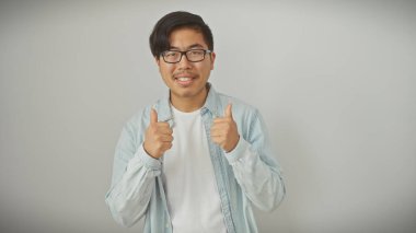 Gözlüklü genç, Asyalı bir adam beyaz arka planda izole edilmiş bir şekilde baş parmak kaldırıyor..
