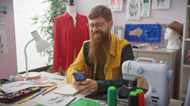 Renkli bir terzi dükkanında sakallı adam dikiş makinesi, kumaş ve manken kullanıyor..