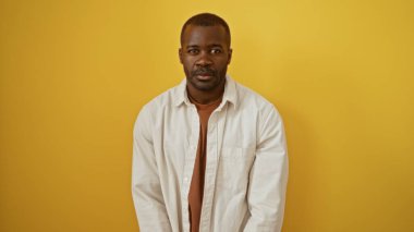 İzole edilmiş sarı arka plan duvarı üzerinde genç ve çekici bir Afrikalı Amerikalı.