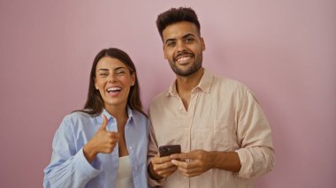 Kadın ve erkek baş parmağıyla gülümsüyor ve telefon pembe arka planda.