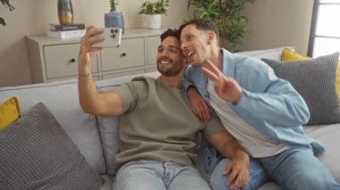 Erkekler oturma odasındaki kanepede selfie çekiyorlar. Aşk ve mutluluğu ifade ediyorlar.