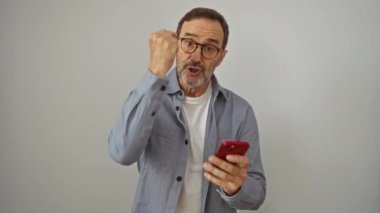 Akıllı telefonlu İspanyol bir adam öfke ve hüsranla bağırıyor, bağırıyor ve izole edilmiş beyaz arka planda rahatsız oluyor.