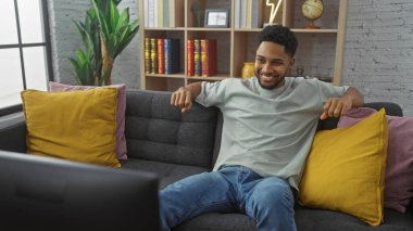 Yakışıklı siyahi adam rahat bir oturma odasında rahat rahat kanepede oturuyor, evde dinleniyor.