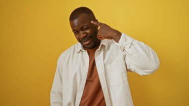 Genç afro-amerikan erkek neşeli bir şekilde sarı bir arka plana karşı hareketler yapıyor, kendinden emin ve çekici bir karakteri vurguluyor..