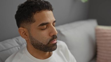 Genç adam evinin oturma odasındaki kanepede dinleniyor gözleri kapalı, huzurlu ve huzurlu bir an sergiliyor..